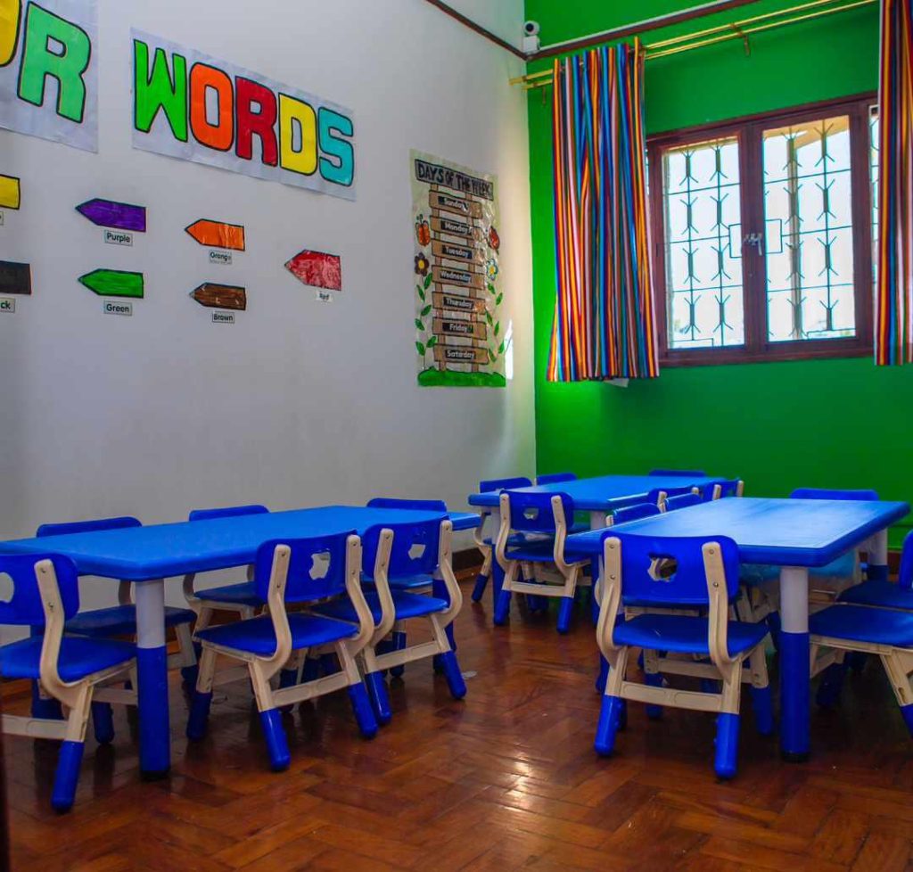 Preschool classroom with blue tables and chairs on a wooden floor