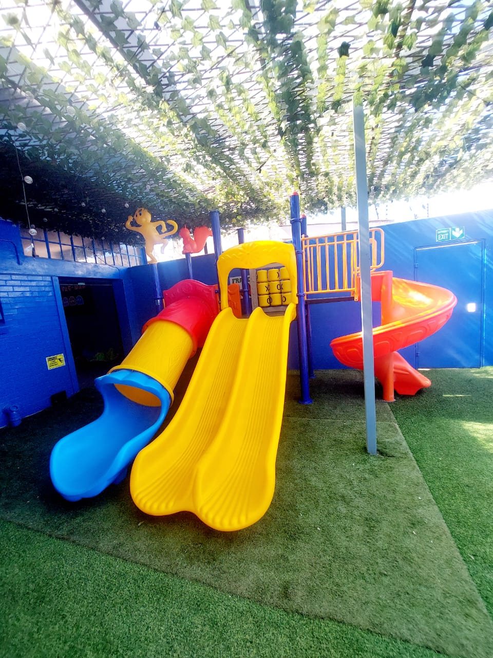 Jungle gym with tube and spiral slides on artificial grass under shade netting
