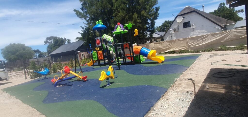 Jungle gym and spring riders on blue and green rubber wet pour surfacing