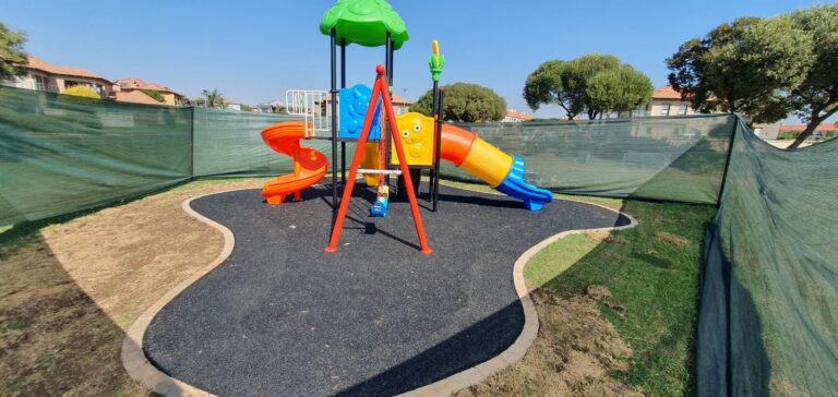 Jungle gym with a swing on a black rubber wet pour island
