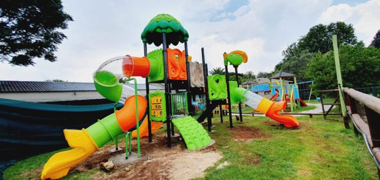 Plastic jungle gym with a tube slide and a climbing ramp on a lawn