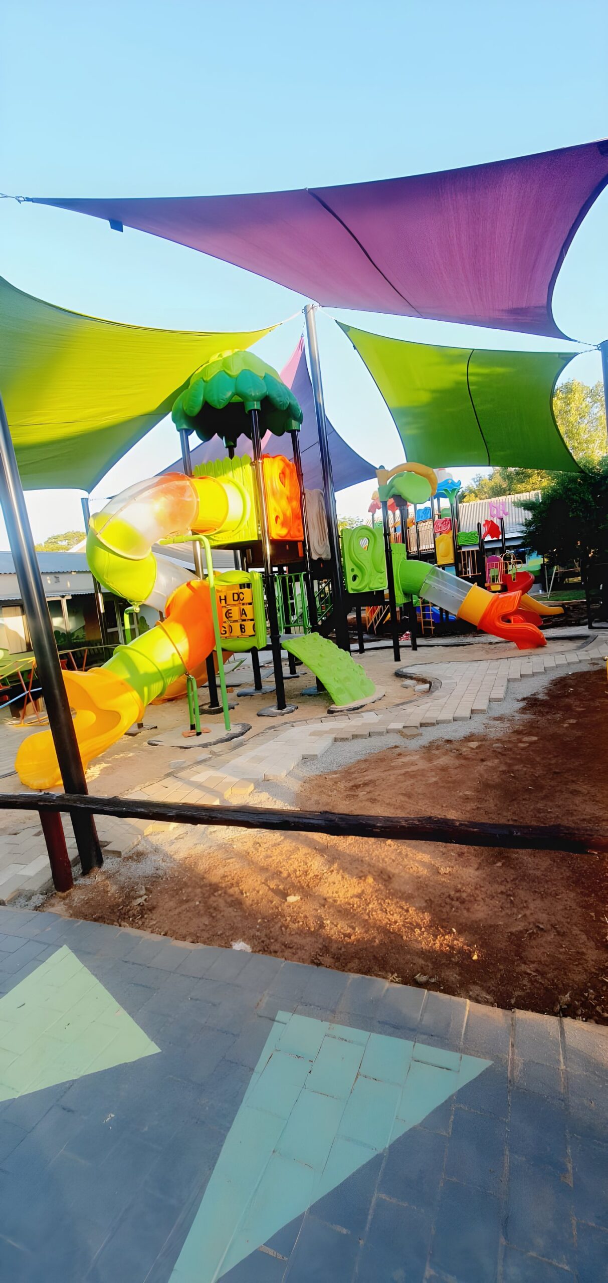 Jungle gyms under colourful shade sails on a paved school playground