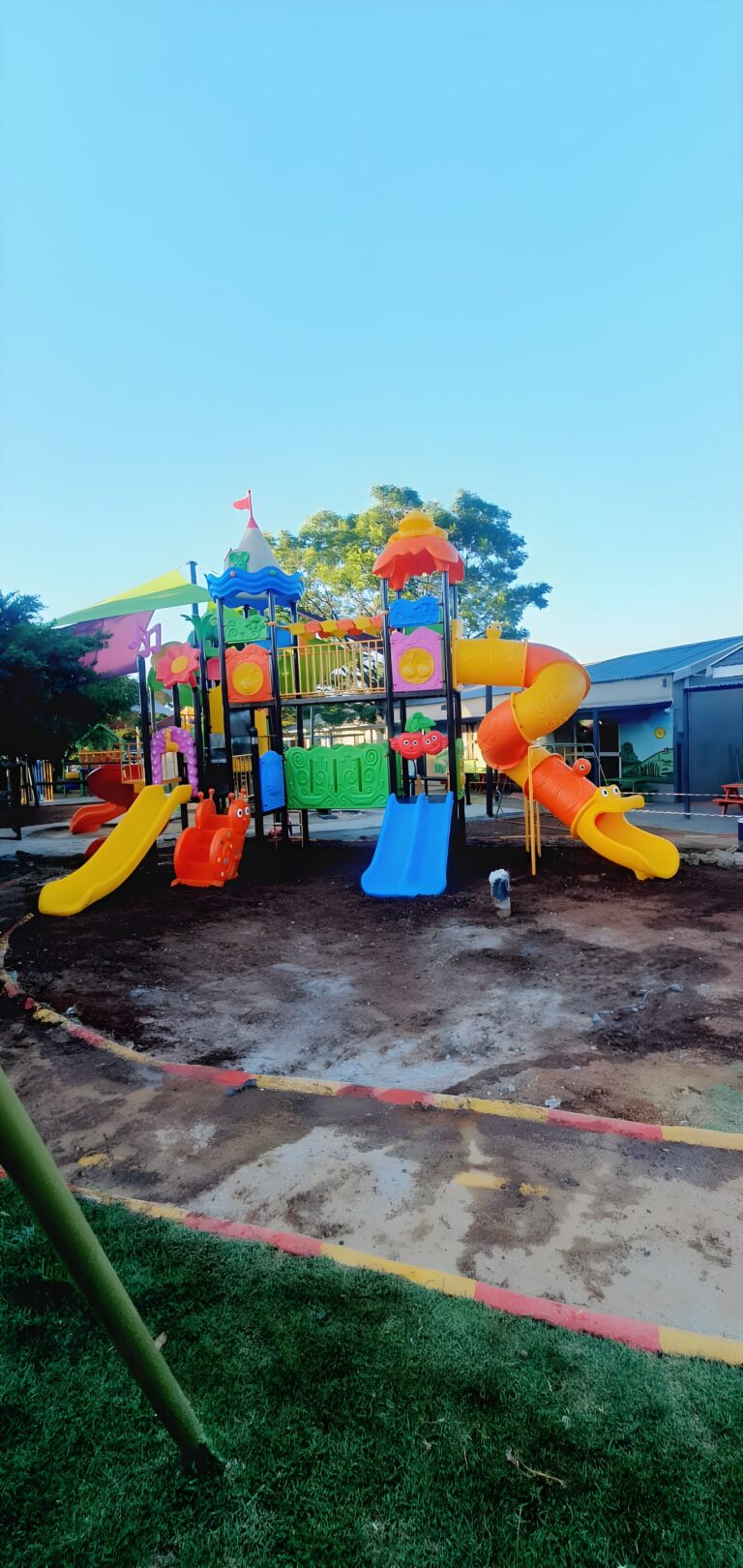 Large colourful jungle gym with spiral and tube slides at a school playground