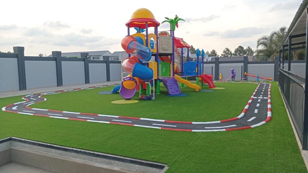 Large plastic jungle gym next to a painted kids bike track on artificial grass