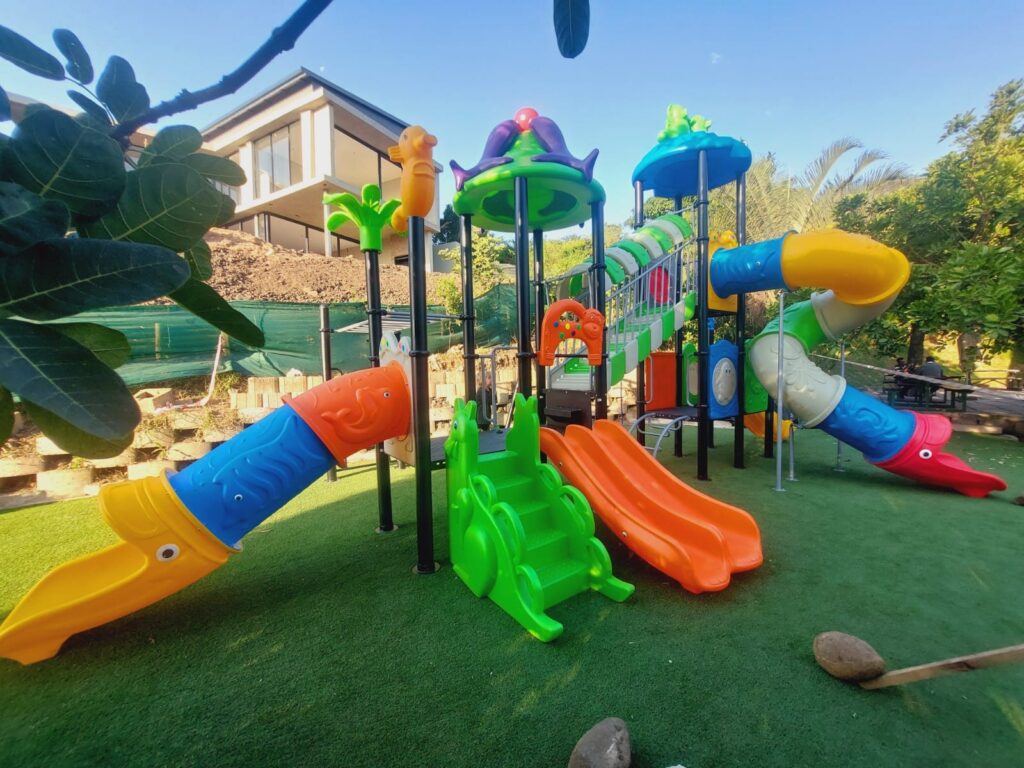 Large plastic jungle gym with tube slides and a climbing wall on artificial grass in a garden, installed by GreenAir