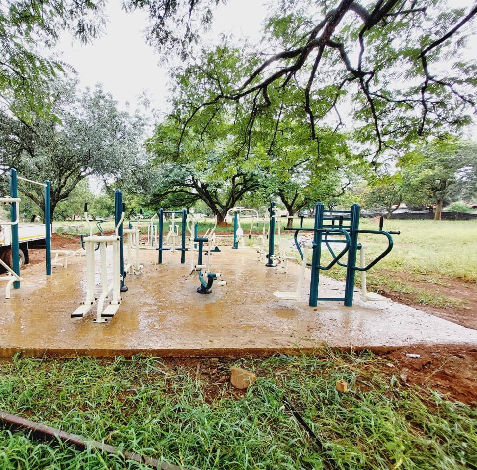 Outdoor gym stations on a concrete slab under trees