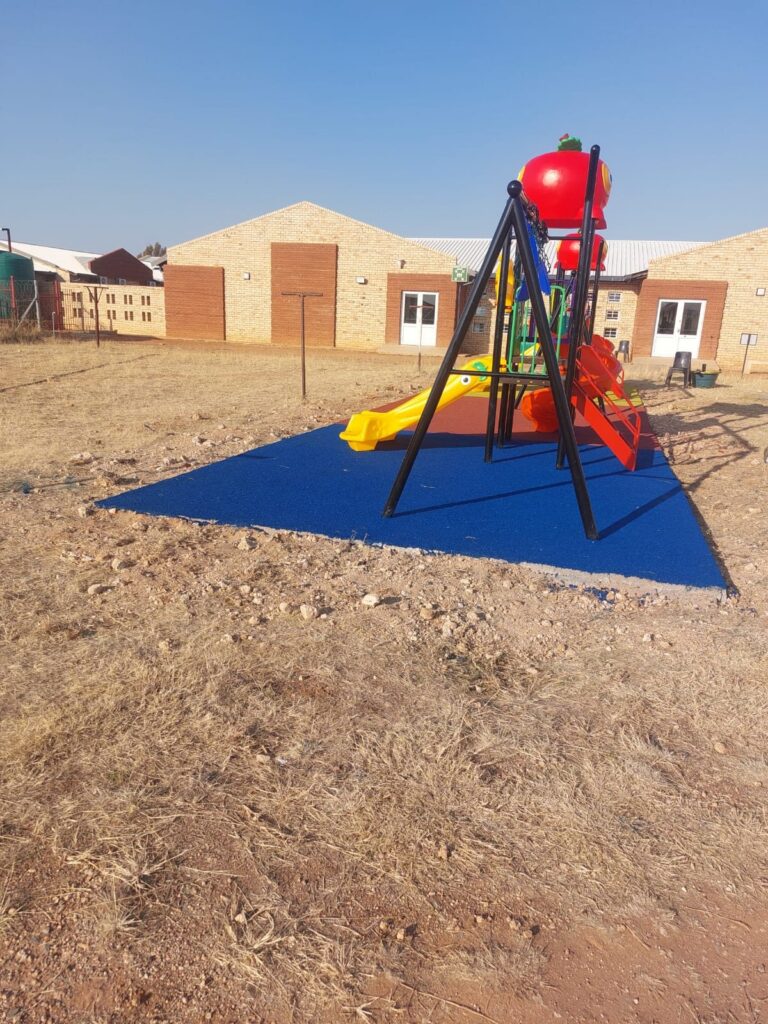 Swing set and jungle gym on blue rubber wet pour surfacing