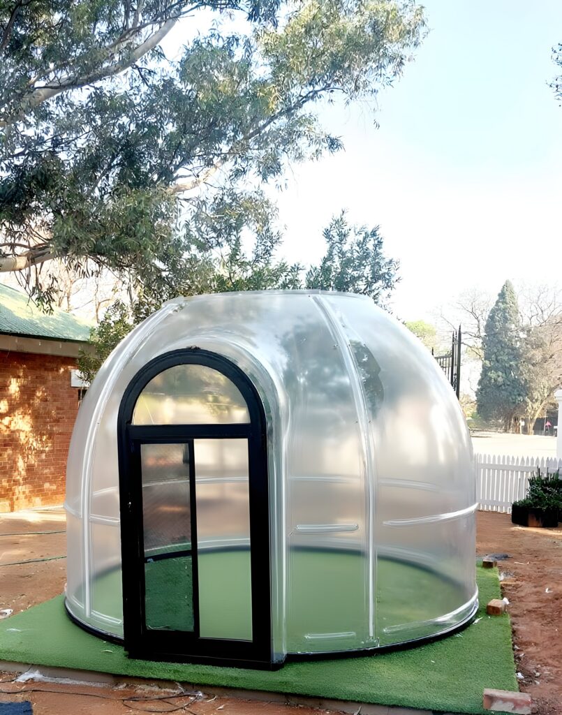 Transparent dome with a black arched door on artificial grass